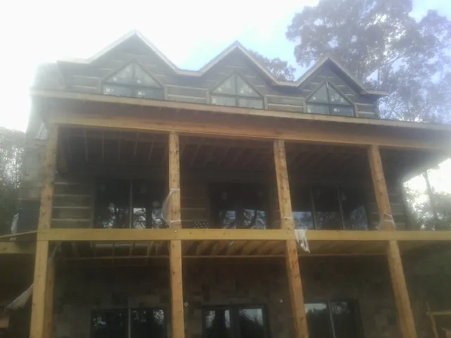 Dormers and porch framing on a large log home under construction — Roof Coating work by our crew in New Hartford