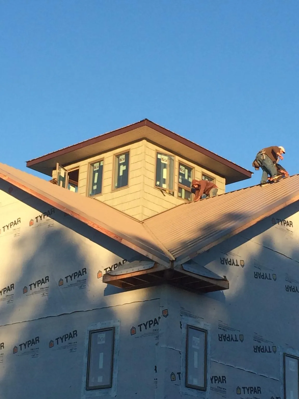 Roofers working around a rooftop cupola on a new metal roof at sunset — Roof Waterproofing in New Hartford by Roofing Brothers
